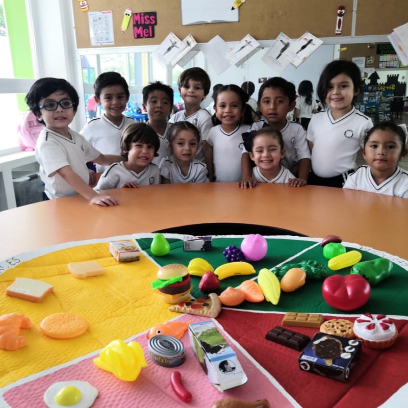 Alumnos de preescolar del Instituto Cumbres Campeche
frente a una mesa con material didáctico.